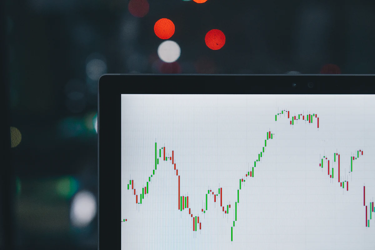 A laptop screen showing a green and red candlestick stock chart