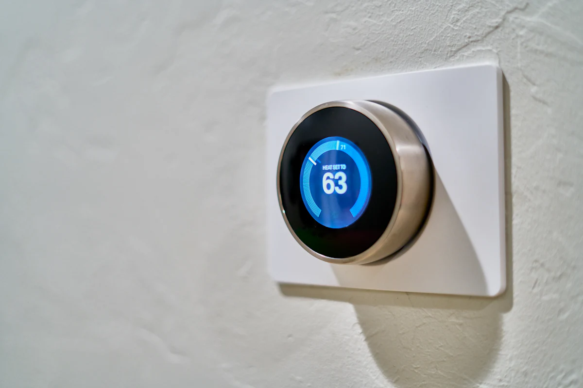 Smart thermostat dial on a wall set to heat