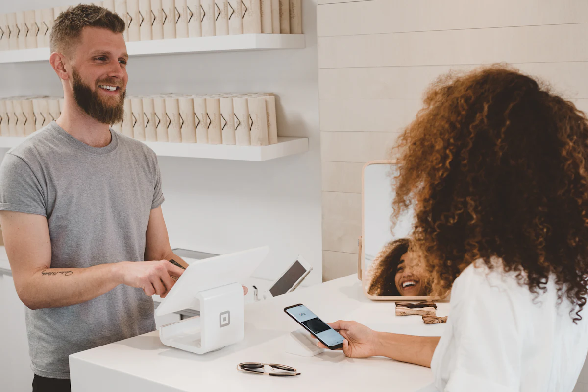 A customer tapping a phone to pay at a store counter