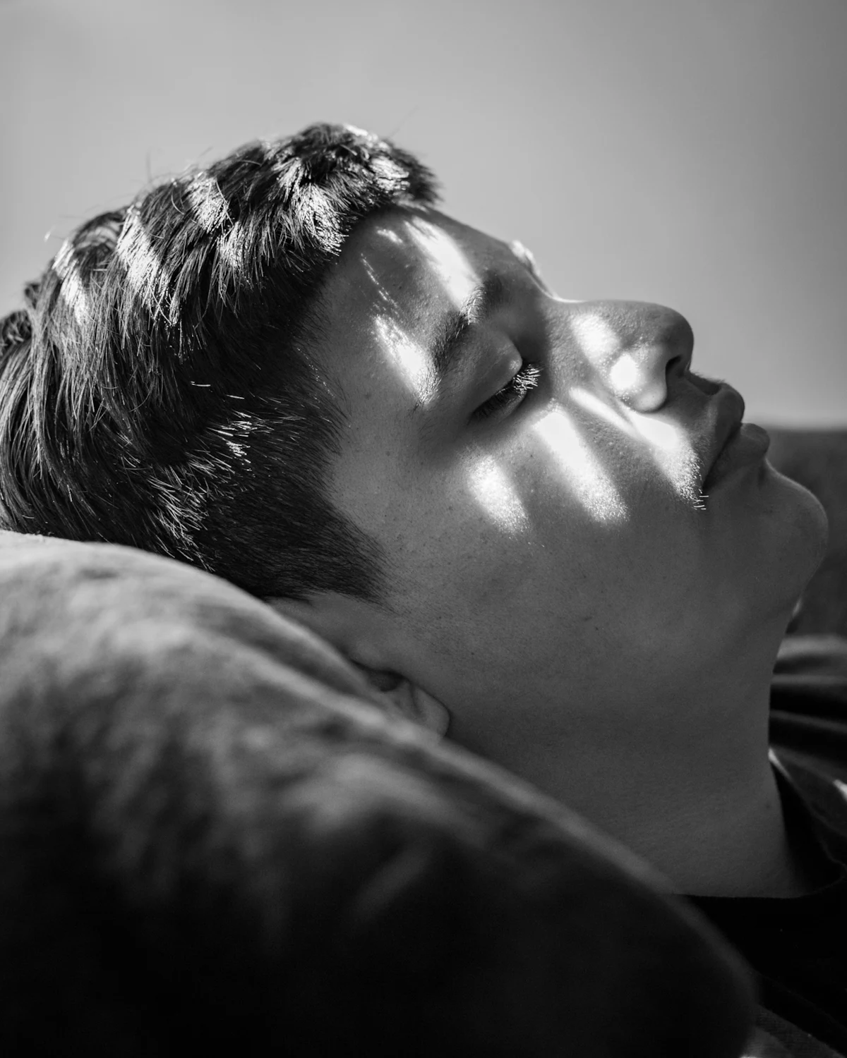 A young man lying awake as light falls across his face