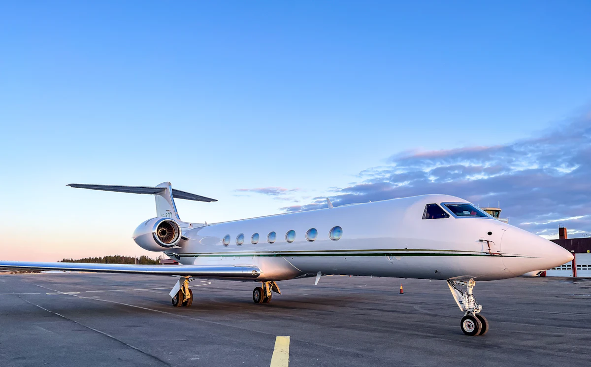 A white Gulfstream private jet parked on an airport tarmac at dusk