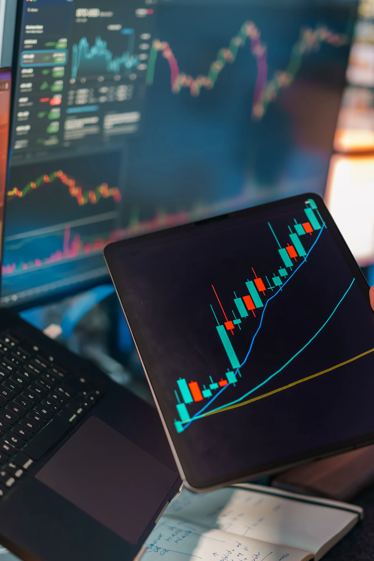 A desk of trading screens and a tablet showing market analytics